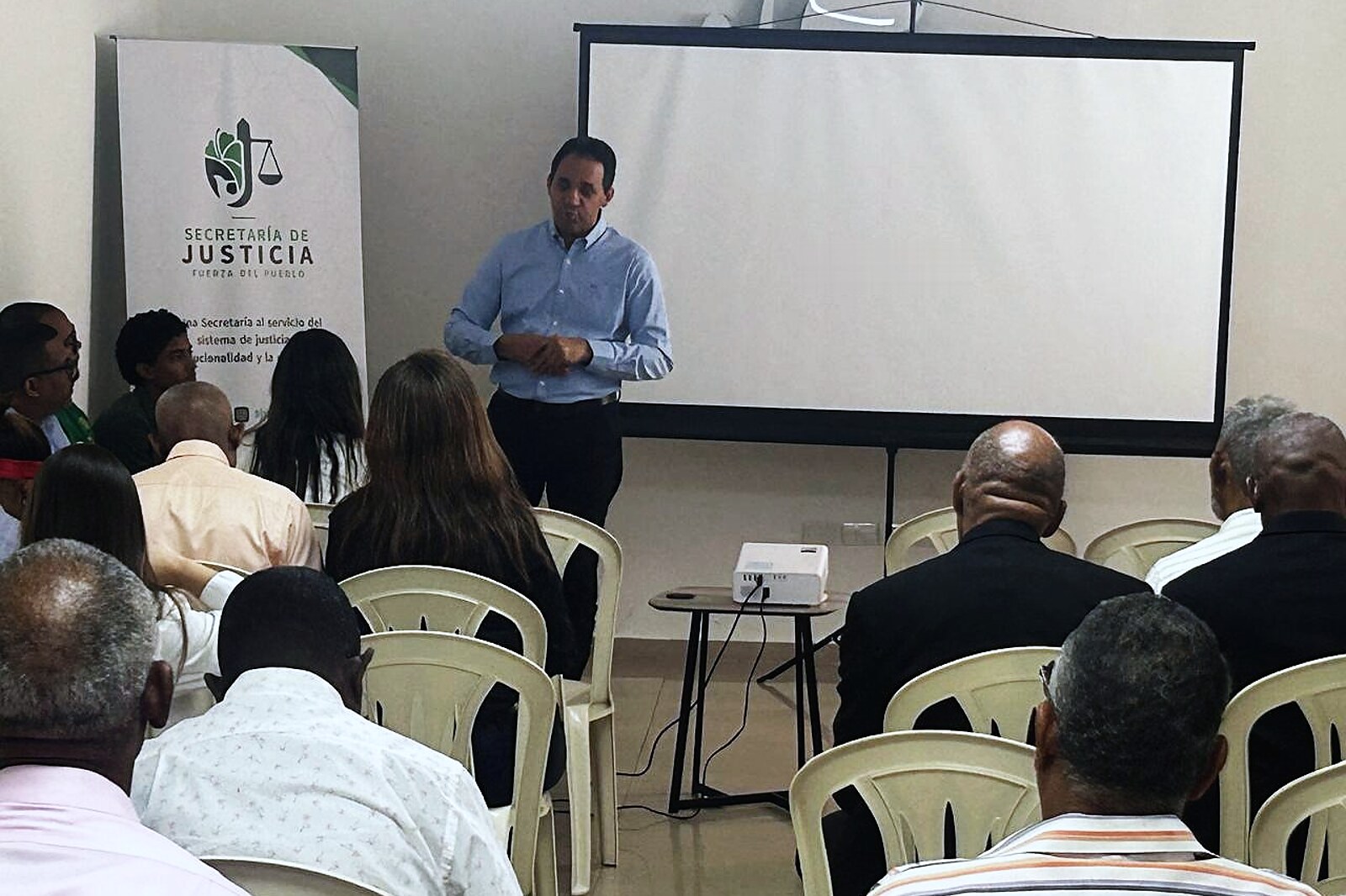 Hotoniel Bonilla, de pie junto al banner de la Secretaría de Justicia, se dirige a los asistentes al inicio del taller.
